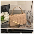 Sac bandoulière nude matelassé avec boucle dorée et poignée sur un bureau en métal - Kaki