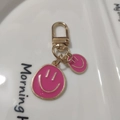 Golden keychain featuring two pink enamel smiley face charms on a white ceramic plate - Small & Large Set Rose Red