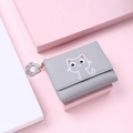 Close-up of grey trifold wallet with white cat print and cat paw zipper charm - Gray