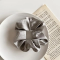 Silver-grey satin scrunchie with silk luster and pleated texture on white plate - Satin Silver Grey