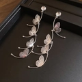 Dettaglio degli orecchini a farfalla argentati con nappe lunghe e strass lucenti - Argento