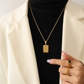 Collana dorata con ciondolo quadrato lettera X e set di anelli indossati da una modella - Lettera X Oro
