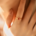 Close-up of a gold ring with wavy band and oval red gemstone worn on a finger - Adjustable Open / Red (KR0045-2)