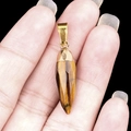 Handheld Tiger Eye stone bullet pendant with a gold-plated metal clasp and faceted finish - Tiger's Eye