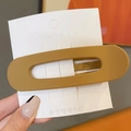 Matte brown oval seamless hair clip displayed on a minimalist white card holder - Ginger Yellow