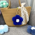 Detail of plush flower charm in teal blue hanging on a textured brown woven bag - Royal Blue