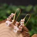 Handmade gold wire-wrapped pearl earrings with carved shell flower and hook design - Shell Flower Pearl Hoop Earrings