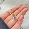 Gros plan d'un collier doré avec pendentif en zircon rond étincelant dans un serti à quatre griffes - Pendentif Anneau