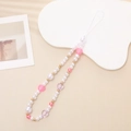 Detalle del colgante para móvil con perlas y corazones rosas sobre soporte blanco - Estilo Corazón de Perla Irregular