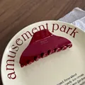 Detail of glossy wine red acetate hair claw clip with elegant gold logo lettering - Triangle Style