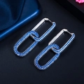 Macro shot of silver interlocking geometric hoop earrings with deep blue and white zircons - White Gold Blue Zirconia