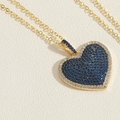 Dettaglio del ciondolo a cuore con pavé di zirconi blu e bianchi su una catena dorata - Zircone a Cuore Blu Reale