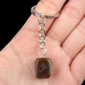 Dark green irregular natural stone keychain with silver metal ring held in palm - India Agate
