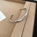 Dettaglio ravvicinato di un bracciale aperto a onde argentate su supporto per gioielli - 2# Bracciale Rigido Aperto a Onda (Argento)