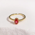 Close-up of adjustable gold ring featuring an oval red gemstone on a textured white stone - Red Gemstone Gold Base