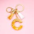 Golden keychain featuring orange and gold resin C-letter pendant with double tassels - Letter C