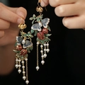Pendientes vintage dorados con mariposa, borlas florales y perlas vistos de cerca - Gancho de Oreja de Mariposa y Granada con Borla / Oro-Verde-Rojo