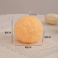 Spherical apricot scented candle with leaf relief, height 6.5cm, on open book background - Macaron Orange Floral Sphere (Wild Neroli)