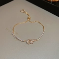 Macro detail of 18k gold plated heart knot tennis bracelet with adjustable slider clasp - Knot Style (Real Gold Plated) / Gold