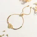 Detail eines Goldherz-Anhängers mit buntem Zirkon-Kreuz auf verstellbarem Gleitarmband - Buchstabe X