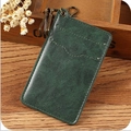 Vintage dark green leather card holder with bronze hook on a rustic wooden background - Green