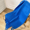 Soft chunky knit blue mohair scarf with fringe tassels draped on a modern leather chair - Sapphire Blue