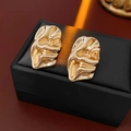 Macro shot of gold abstract lava texture stud earrings on a luxury matte jewelry box - Gold / Gold