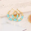 Detalle macro de pendientes esmaltados en oro y azul cielo sobre fondo mármol - Azul Cielo