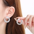 Dettaglio dell'orecchino a U in argento con trama a spirale e perla su modella - Color Acciaio
