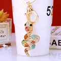 Golden snake keychain pendant with colorful rhinestones on a white porcelain cup background - Multicolor Snake