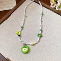 Détail du collier de perles avec pendentifs pomme verte et étoile sur bois - Collier Pomme Acrylique Étoile de Mer Perle
