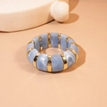 Detail of blue marble acrylic cuff bracelet with gold metal spacers on beige background - Blue