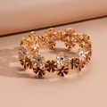 Détail macro du bracelet élastique à fleurs en émail coloré avec finition dorée vintage - Marron