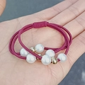 Elastic burgundy woven hair tie with white pearls and gold beads shown in hand - Burgundy