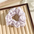 Purple and white checkered scrunchie in textured seersucker fabric on a velvet tray - Grid Purple