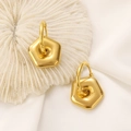 Detailed close-up of golden hexagonal geometric earrings on white coral and silk fabric - 18K Gold Pentagon (X099)