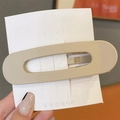 Pinza de pelo ovalada grande color beige mate en tarjeta blanca sostenida en la mano - Blanco Roto