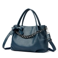 Dark blue leather tote bag with chain strap and bow detail in a minimalist studio setting - Blue