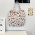 Detail of quilted cartoon tote bag with purple woven ropes hanging on a minimal white wall - Cat Angel