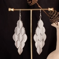 Detail view of silver layered leaf earrings hanging on a display stand with black background - Textured Leaf / Silver