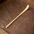 Single natural bamboo tea spoon for matcha ceremony on textured brown fabric mat - White Bamboo Tea Scoop