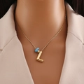 Close-up of gold chain necklace featuring a blue eye bead and letter Z pendant on a model - Gold Letter L