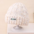 Detail der Strickstruktur einer cremefarbenen Mütze mit bunten Punkten und Aufnäher - Kinder 3-10 Jahre (Dehnbar) / Hellbeige
