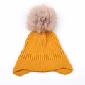 Dettaglio del berretto a maglia giallo senape con un soffice pompon di pelliccia rosa - Giallo Zenzero - Berretto in Maglia