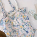 Detail shot of canvas tote bag featuring colorful floral and rabbit illustrations - Blue Green Floral