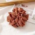 Close-up of a reddish-brown fabric scrunchie with delicate gold bead edges on linen cloth - Pleated Orange