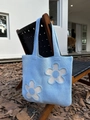Detail of light blue knit tote bag with large floral appliques on a wooden chair - Light Blue