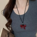 Detailed view of a glossy red bow pendant on a black cord necklace worn by a model - 21# Necklace - Red - Glossy Bow