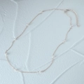 Detailed close-up of a delicate silver pearl necklace on a white textured background - Silver Thin Chain-Equidistant Pearl Minimalist