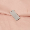 Dettaglio macro della targhetta rettangolare in acciaio inox lucido su tessuto rosa - Acciaio Corto (30mm*12mm)